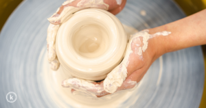 Two hands surrounding wet clay